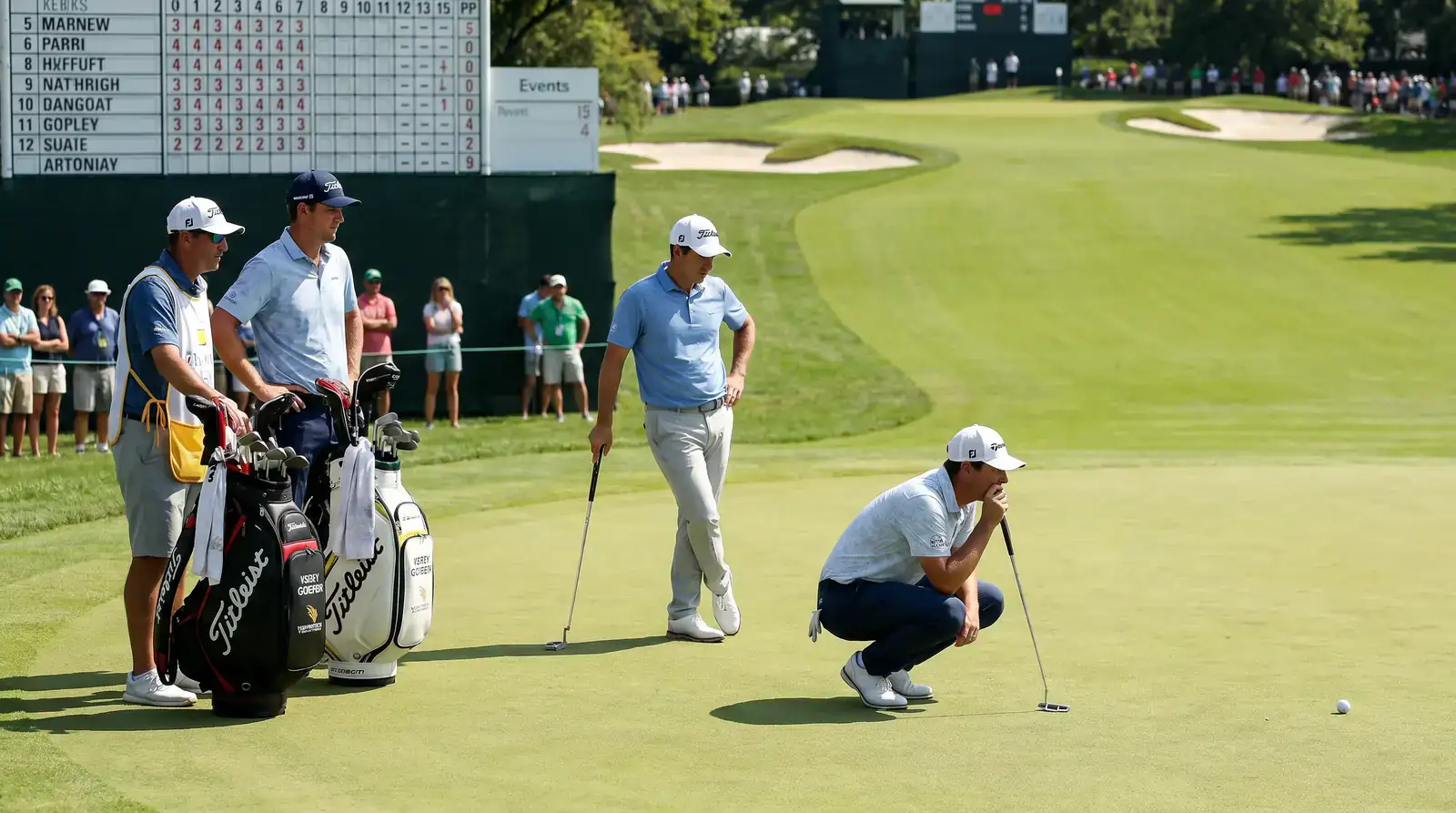 Three-ball group gathered on a putting green during a tournament round